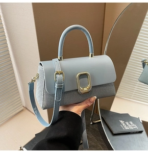 Detail showing mixed texture design with blue leather flap and grey woven fabric body