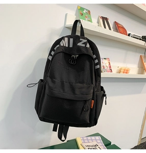 Detail of black waterproof nylon backpack with orange tag and drawstring side pockets