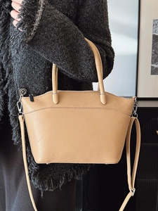 Minimalist beige bucket bag with diagonal stitching and adjustable strap shown on model