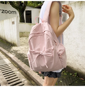 Detail view of pink ballet-style backpack with bow ribbon decoration and side zipper pockets