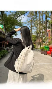 Side view of a minimalist cream-colored nylon backpack shown on a model for daily commute