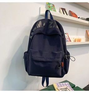 Navy blue canvas backpack featuring minimalist black letter printing and side orange label