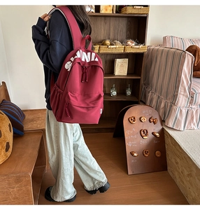 Detail of burgundy letter print backpack with red and white woven zipper pullers