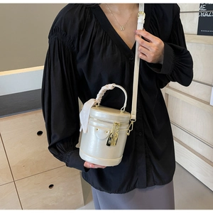 Close-up of cream cylinder handbag with silk scarf detail and golden lock charm