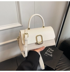 Detail of white woven crossbody bag with litchi grain leather flap and gold metal buckle