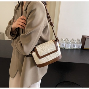 Détail du sac bandoulière tissé blanc avec bordure en cuir marron et lettrage fashion