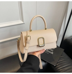 Detail of beige woven leather handbag with a gold-tone rectangular metal buckle and strap