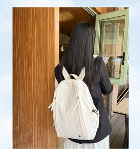 Close-up of the large capacity beige backpack with functional side drawstring pocket