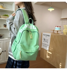 Detailed view of mint green school backpack with white letter print and side pockets