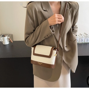 Détail du sac seau tissé avec bordure en cuir marron et bandoulière élégante