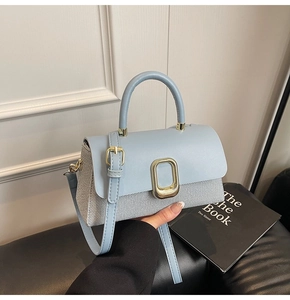 Detailed shot of a light blue and grey spliced leather handbag with a gold metal buckle