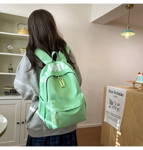 Detail of mint green backpack with white letter print and durable nylon texture