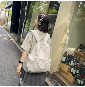 Detail of cream backpack with bow drawstring design and side zipper pocket for students