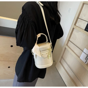 Détail du sac seau cylindrique crème avec foulard en soie et finitions dorées