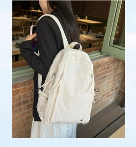 Detailed side view of ivory nylon backpack with drawstring and zipper pockets