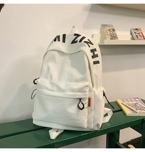Detail of the white canvas backpack featuring AI ZIZHI text and orange label on front pocket