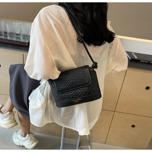 Détail du sac seau noir tressé avec texte Fashion & Bag et bandoulière à nœud décoratif