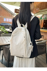 Detail of off-white nylon backpack showing subtle wrinkled texture and bear metal emblem