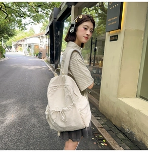 Detail shot of beige ballet-style backpack with drawstring bow and side water bottle pocket