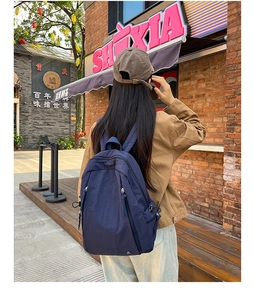 Detailed side view of navy blue nylon backpack with adjustable drawstring side pockets