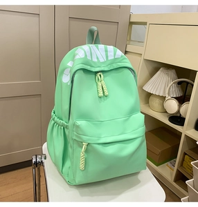 Detailed view of mint green nylon backpack featuring white PINK print and zipper pullers