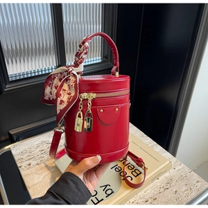 Détail du sac cylindre rouge avec poignée en foulard et ferrures métalliques dorées