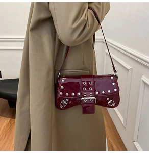 Detail view of dark burgundy punk style underarm bag with silver rivets and leather buckle