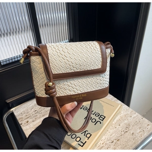 Détail du sac seau en cuir tressé blanc avec surpiqûres marron et détails dorés