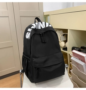 Detail of black nylon backpack with SIND lettering, front zip pocket and side mesh pouch