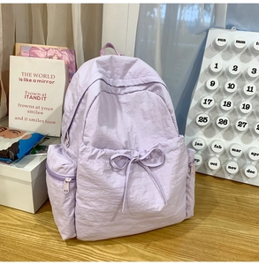 Detailed view of lavender backpack with bow accent on light wooden surface