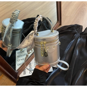 Détail du sac cylindre argenté avec poignée en foulard et breloques de cadenas dorés