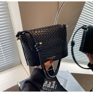 Détail de la texture tressée noire et texte doré sur le sac seau élégant pour femmes