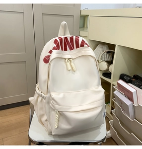 Close-up of cream backpack with red CHINA print and woven rope zipper pullers
