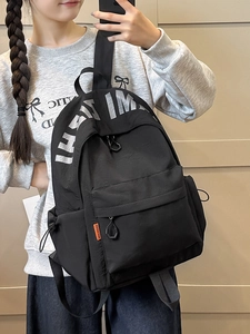 Minimalist black nylon backpack with orange tag and silver lettering for students