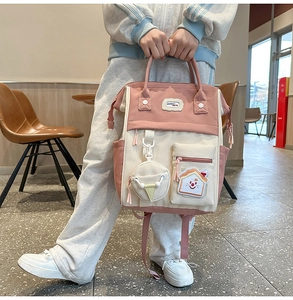 Détail du sac à dos bicolore rose et beige avec doubles poignées et breloques de mode
