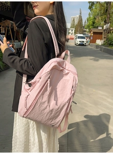 Detail view of light pink nylon backpack with adjustable buckles and water resistant texture