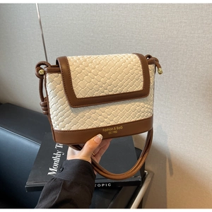 Détail du tissu tressé crème et de la bandoulière en cuir marron avec boucle dorée