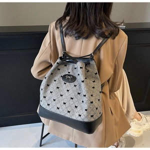 Détail d'un sac à dos gris à motif nœuds avec lanières en cuir porté par un mannequin