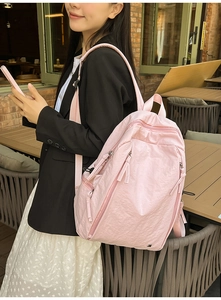 Detail of light pink waterproof nylon backpack showing front zip pocket and fabric texture