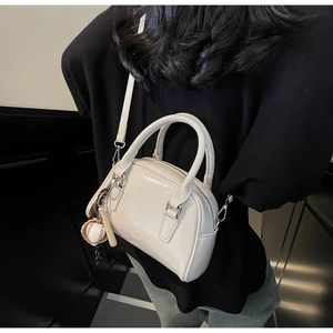 Detail of cream glossy leather mini Boston bag with a baseball charm and shoulder strap