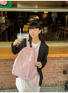Detail showing the pink nylon backpack texture and dual zipper design with drawstrings