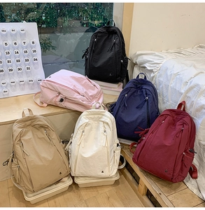 Collection of minimalist nylon backpacks in six colors displayed on a wooden staircase