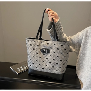 Détail du sac cabas gris matelassé avec imprimés nœuds noirs et poignées en cuir