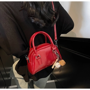 Detail of red bowling bag in shiny leather with mini baseball glove and bat charms