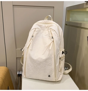 Detail of minimalist beige nylon backpack with double zipper pockets and small metal logo