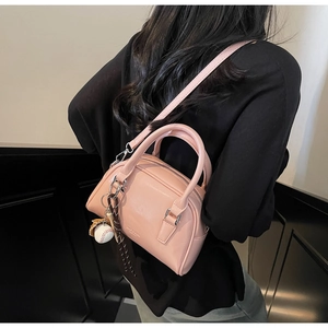 Pink mini Boston bag with baseball charm shown as a crossbody on a model back view
