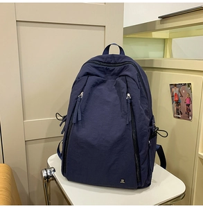 Detail of the dark blue nylon backpack showing the silver metal bear logo and front zippers