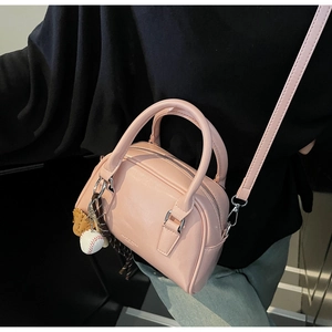 Pink Boston style handbag with baseball glove charm and adjustable shoulder strap accessory