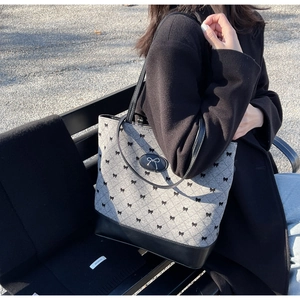 Gros plan du sac cabas gris matelassé avec broderies nœuds noirs et cuir