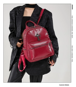 Detail of dark red punk backpack with silver metal studs and cross pendant design